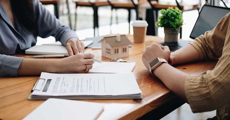 A couple compares rental and homeownership budgets at a kitchen table beside housing documents.