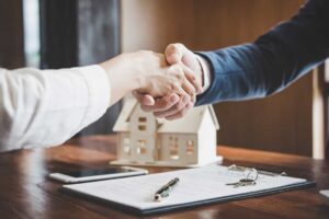 First-time buyers review home documents at a kitchen table beside a calculator, keys, and inspection notes.